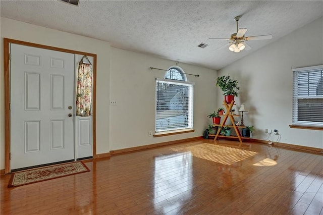 entrance foyer featuring hardwood / wood-style flooring, vaulted ceiling, plenty of natural light, and a textured ceiling