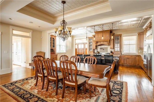 dining area with a raised ceiling, ornamental molding, and a healthy amount of sunlight