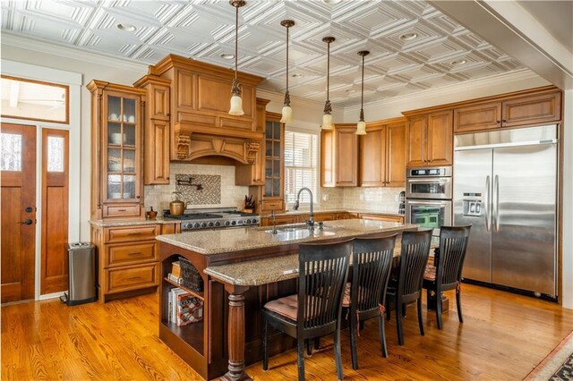 kitchen with sink, a breakfast bar area, decorative light fixtures, a center island with sink, and appliances with stainless steel finishes