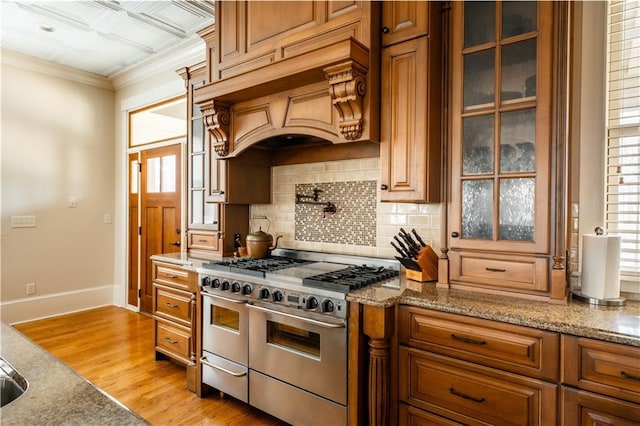 kitchen with double oven range, premium range hood, stone counters, and light wood-type flooring