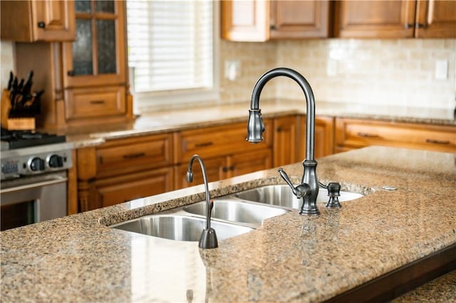 kitchen with light stone countertops, sink, and stainless steel range with gas cooktop