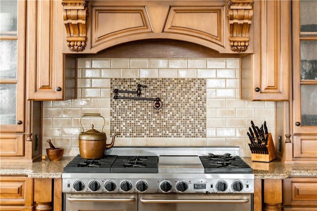 kitchen with range with two ovens, custom exhaust hood, light stone countertops, and decorative backsplash