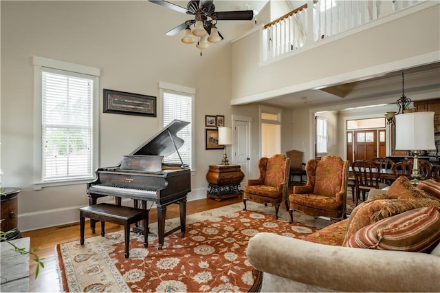 living area with plenty of natural light, light hardwood / wood-style floors, ceiling fan, and a high ceiling