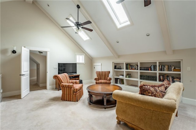 living room with ceiling fan, beam ceiling, a skylight, and light carpet