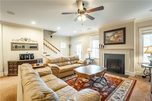 living room with ceiling fan, ornamental molding, a healthy amount of sunlight, and light colored carpet