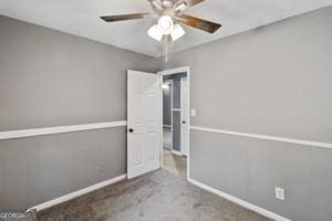 unfurnished room featuring baseboards, carpet floors, and ceiling fan