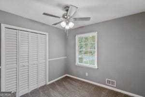 unfurnished bedroom with a closet, ceiling fan, carpet floors, baseboards, and visible vents