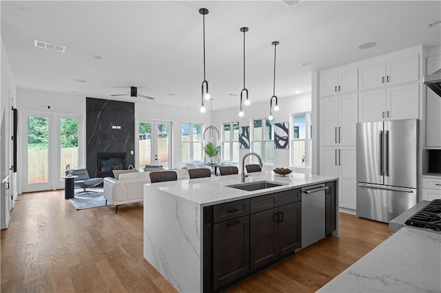 kitchen with stainless steel appliances, light stone counters, white cabinetry, and sink