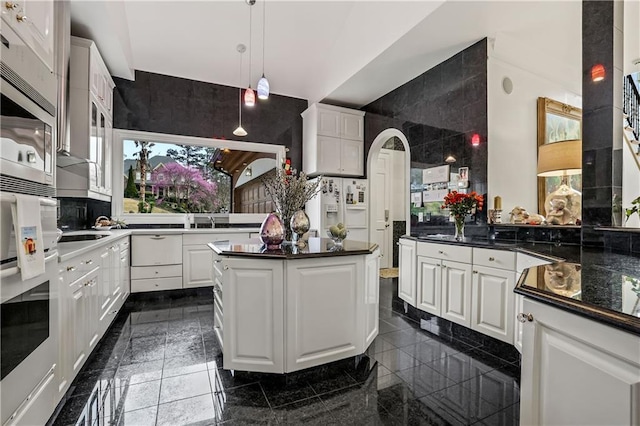 kitchen with plenty of natural light, white fridge with ice dispenser, and white cabinetry