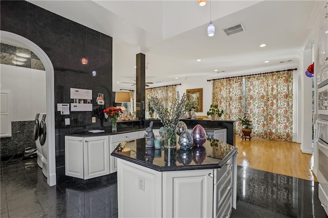 kitchen with white cabinetry, a center island, ceiling fan, dark wood-type flooring, and tile walls