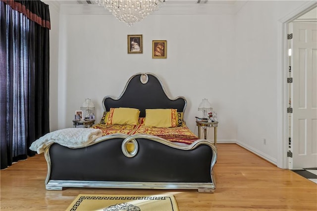 bedroom featuring wood-type flooring, ornamental molding, and a notable chandelier