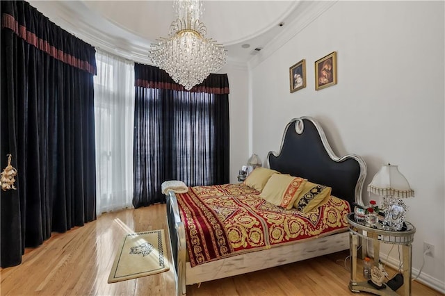 bedroom featuring hardwood / wood-style flooring, a notable chandelier, and crown molding