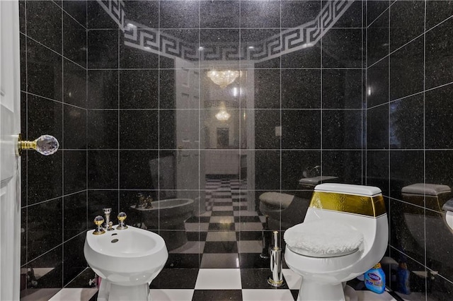 bathroom with toilet, tile walls, and a bidet