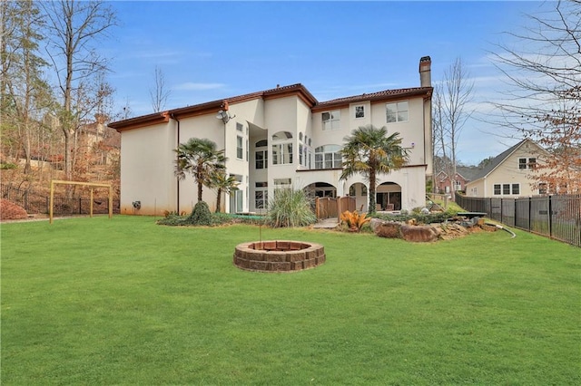 rear view of property with a yard, a balcony, and a fire pit