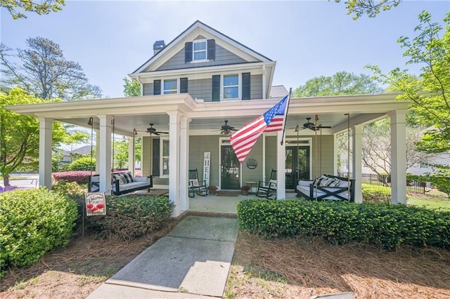 view of front of property featuring a porch, a chimney, fence, and a ceiling fan
