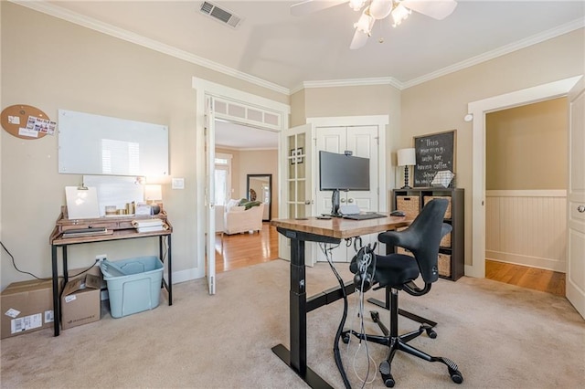 office area with visible vents, ornamental molding, a ceiling fan, carpet, and wainscoting