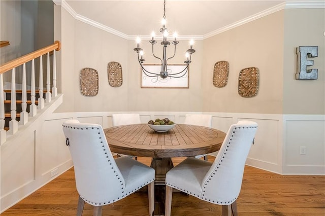 dining area with a decorative wall, light wood-style flooring, a chandelier, and crown molding