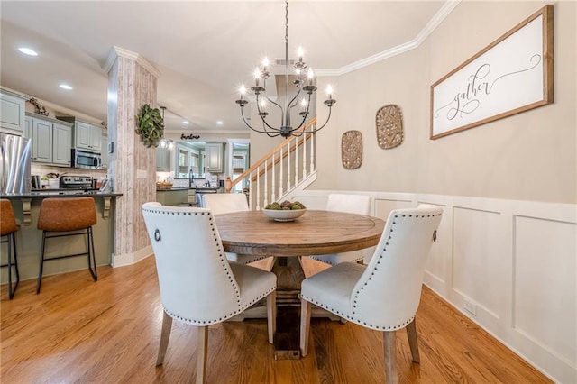 dining space with a notable chandelier, a decorative wall, ornamental molding, stairway, and light wood finished floors