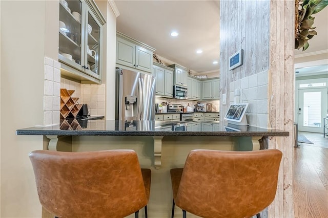 kitchen with tasteful backsplash, ornamental molding, a peninsula, glass insert cabinets, and stainless steel appliances