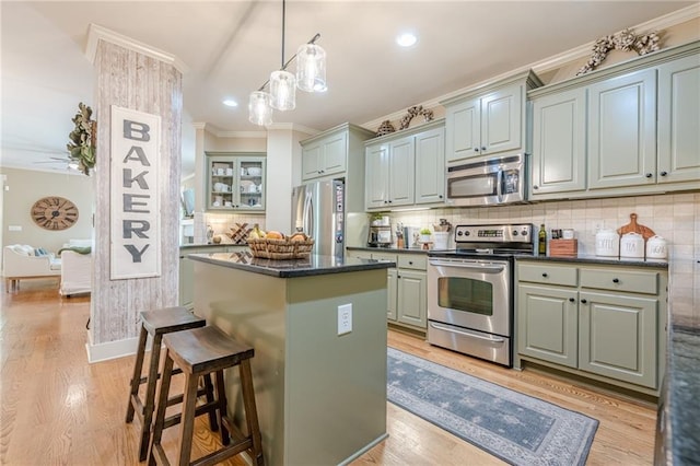 kitchen with crown molding, tasteful backsplash, light wood-type flooring, a center island, and stainless steel appliances