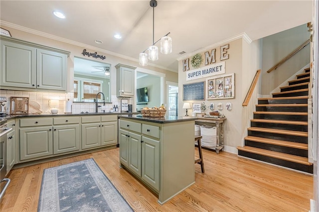 kitchen featuring light wood-type flooring, a center island, dark countertops, decorative backsplash, and a sink
