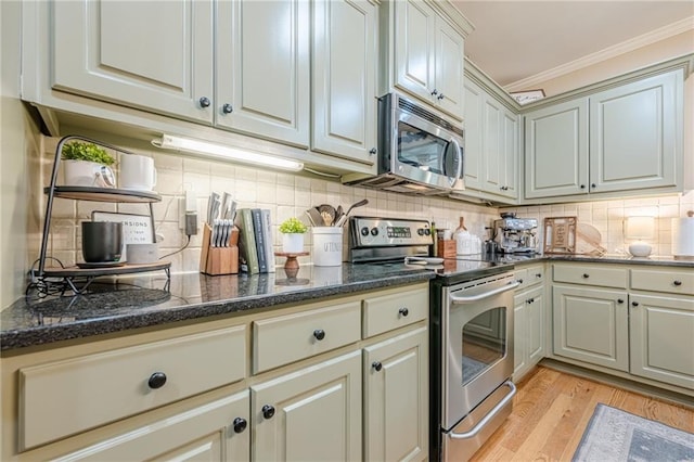 kitchen with light wood-style flooring, ornamental molding, backsplash, and appliances with stainless steel finishes