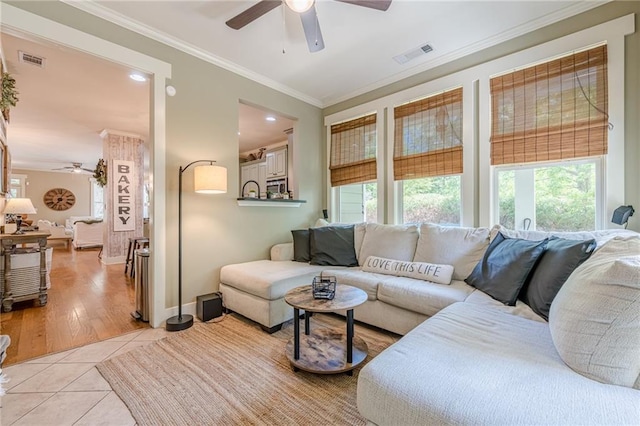 living area featuring visible vents, a ceiling fan, ornamental molding, and light tile patterned flooring