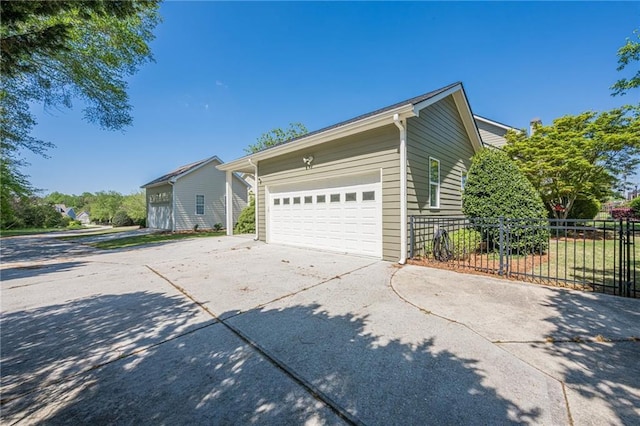 view of property exterior with fence, a garage, and concrete driveway