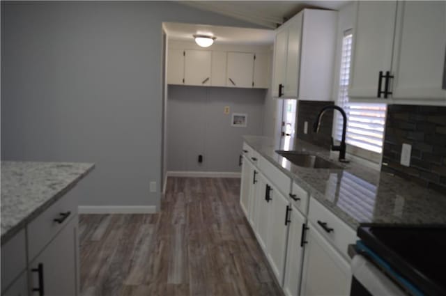 kitchen with light stone counters, dark hardwood / wood-style floors, sink, and white cabinets