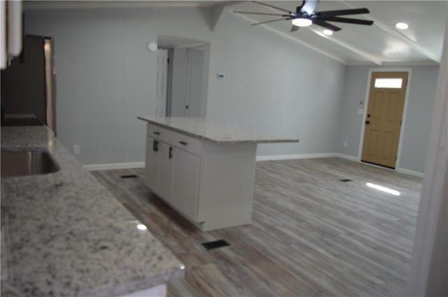 kitchen with a center island, vaulted ceiling, light wood-type flooring, black refrigerator, and white cabinets