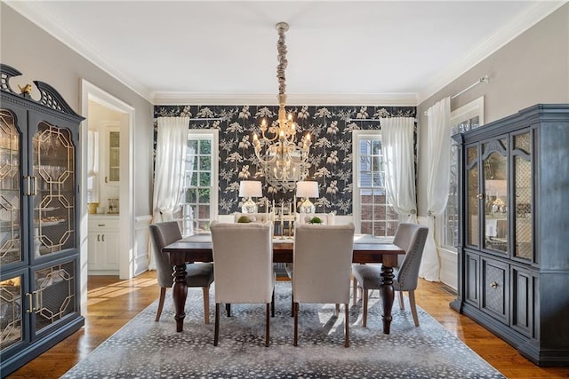 dining area featuring hardwood / wood-style flooring, ornamental molding, and an inviting chandelier