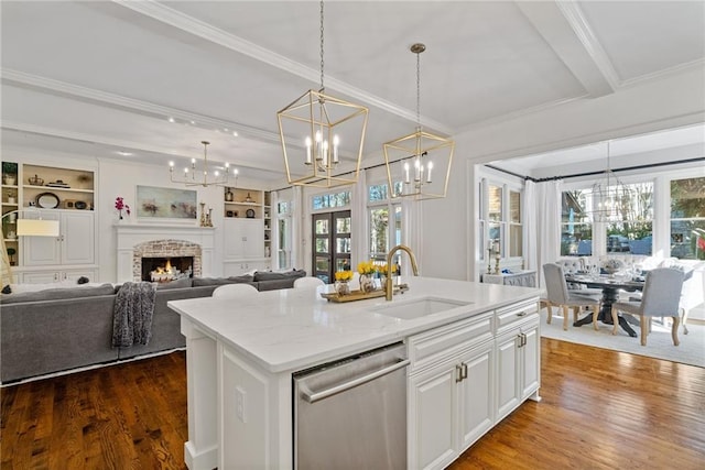 kitchen featuring built in shelves, sink, stainless steel dishwasher, and a center island with sink