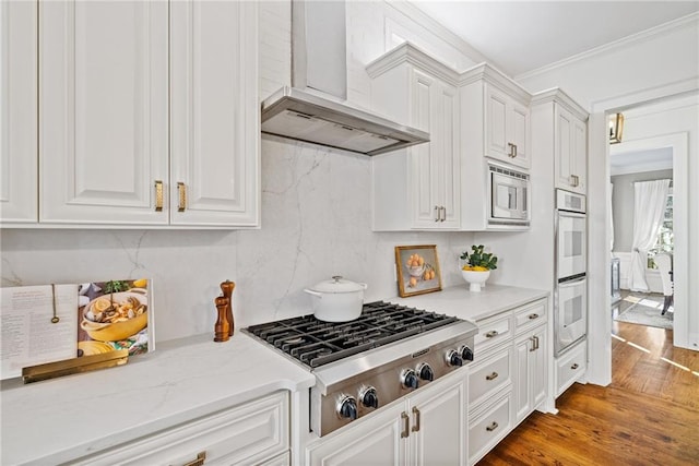 kitchen with premium range hood, ornamental molding, white cabinetry, wood-type flooring, and stainless steel appliances