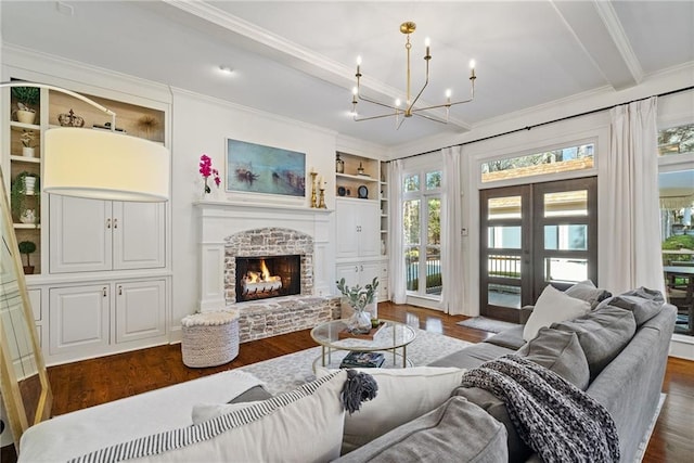 living room featuring built in shelves, dark hardwood / wood-style flooring, a brick fireplace, and french doors