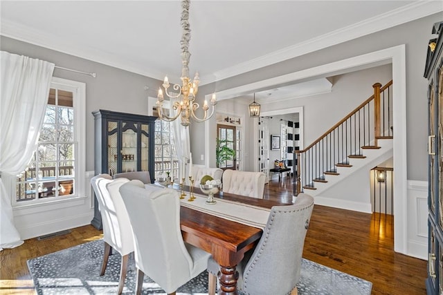 dining area with a wealth of natural light, a chandelier, dark wood-type flooring, and ornamental molding