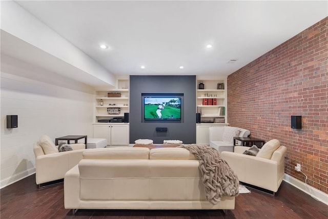 living room featuring built in shelves, dark wood-type flooring, and brick wall