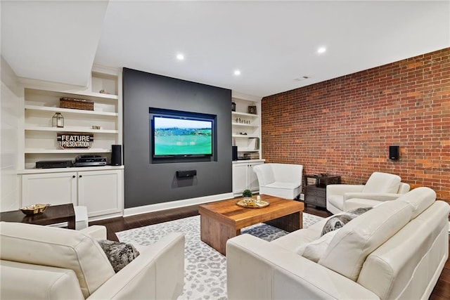 living room with built in shelves, dark wood-type flooring, and brick wall