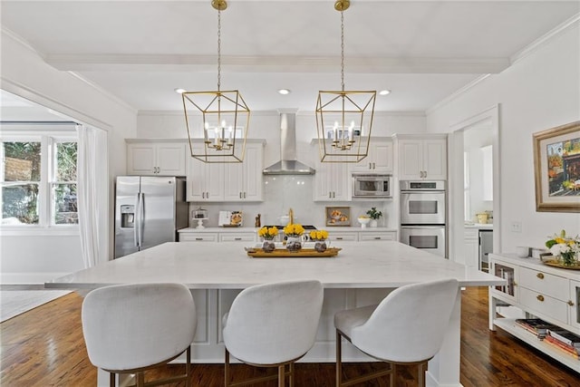 kitchen featuring a spacious island, hanging light fixtures, wall chimney exhaust hood, ornamental molding, and stainless steel appliances