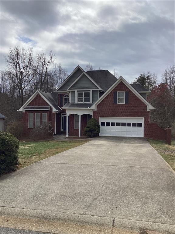 craftsman inspired home with a garage, concrete driveway, brick siding, and a front lawn