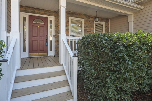 view of exterior entry featuring stone siding and covered porch