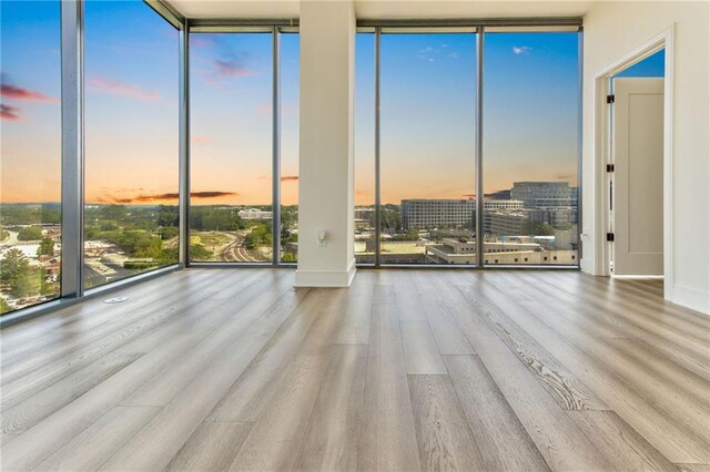 unfurnished room with light wood-type flooring and a wall of windows