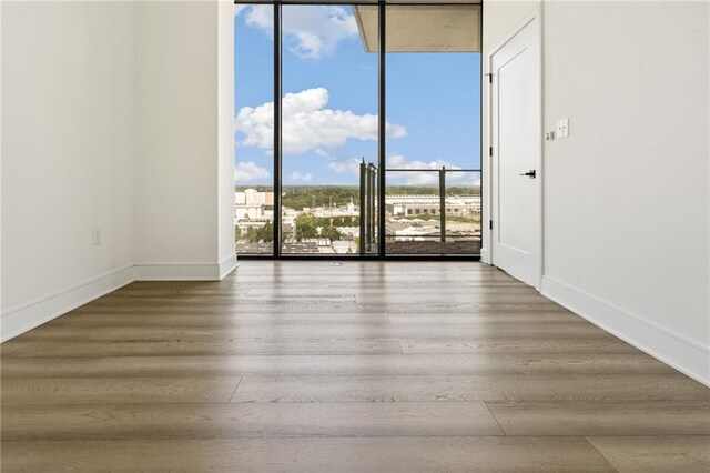 empty room with wood-type flooring and a wall of windows