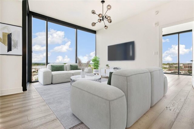 living room featuring light wood-type flooring, a notable chandelier, floor to ceiling windows, and a wealth of natural light