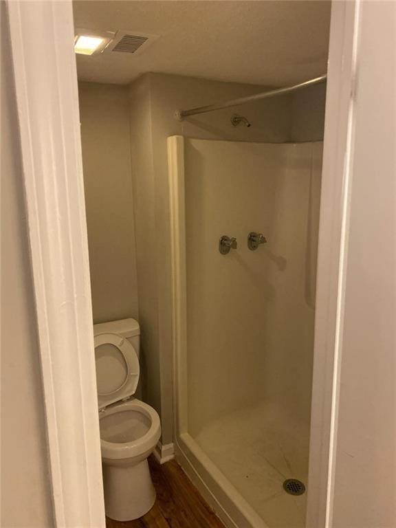 bathroom featuring a shower, hardwood / wood-style flooring, and toilet