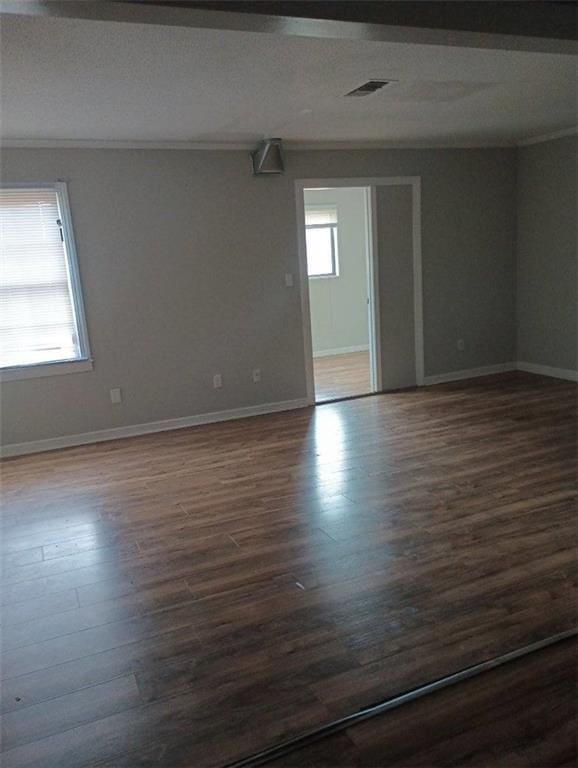 empty room featuring crown molding and dark hardwood / wood-style flooring