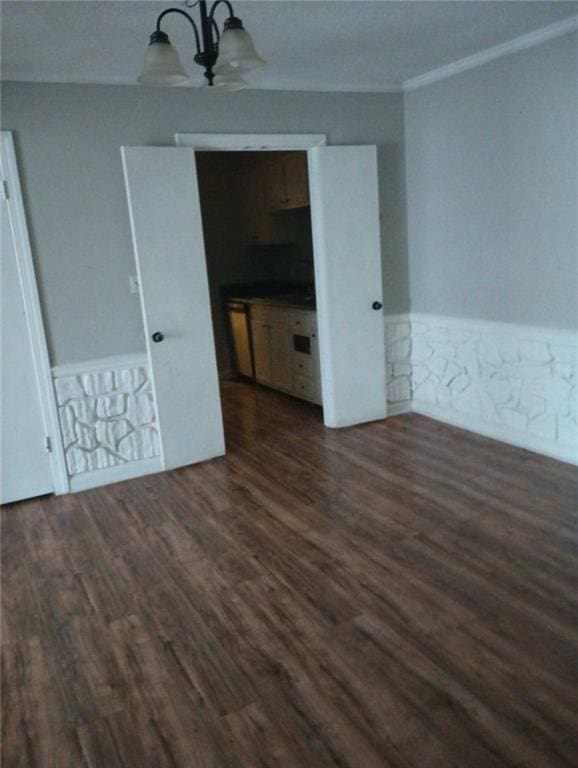 unfurnished room featuring crown molding, dark hardwood / wood-style floors, and a chandelier