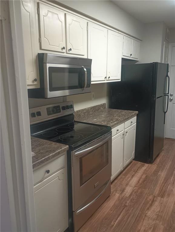 172 Rue Fontaine, Lithonia, GA 30038 - kitchen featuring appliances with stainless steel finishes, dark wood-type flooring, dark countertops, and white cabinets