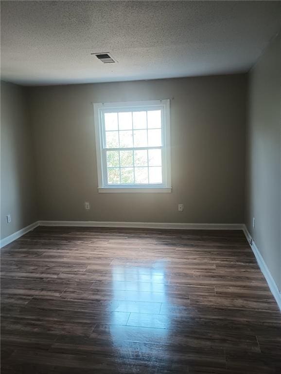 unfurnished room with dark hardwood / wood-style flooring and a textured ceiling