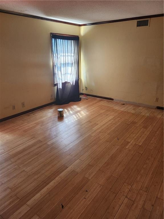 spare room featuring light hardwood / wood-style flooring, a textured ceiling, and crown molding