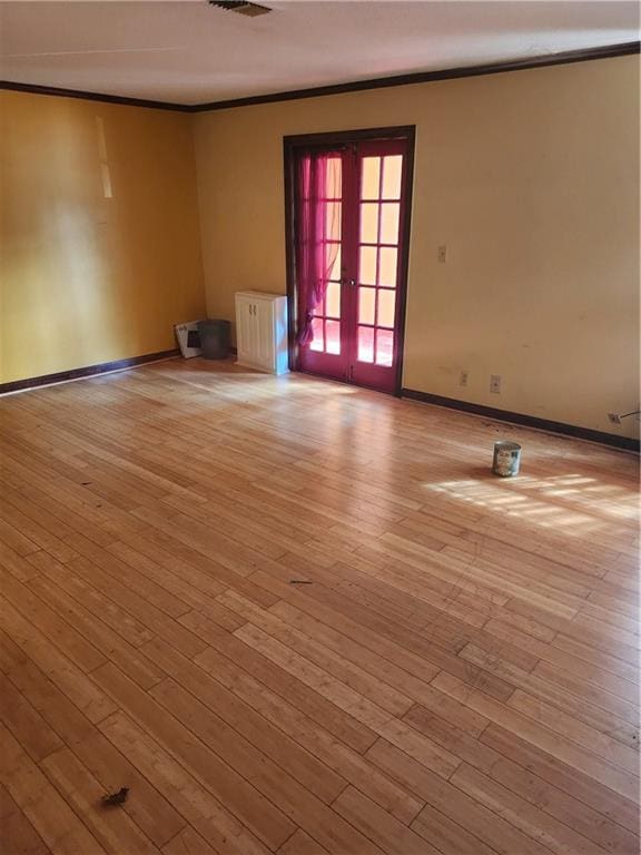 unfurnished room with ornamental molding, french doors, radiator heating unit, and light hardwood / wood-style floors